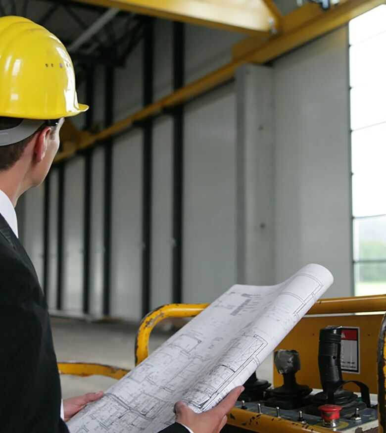 Engineer with hard hat examining blueprints at construction site