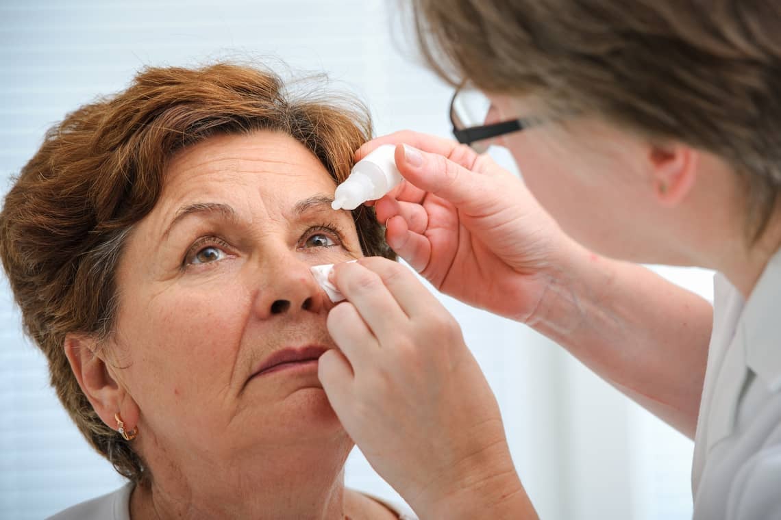 Doctor helps the patient and gives the eye drops