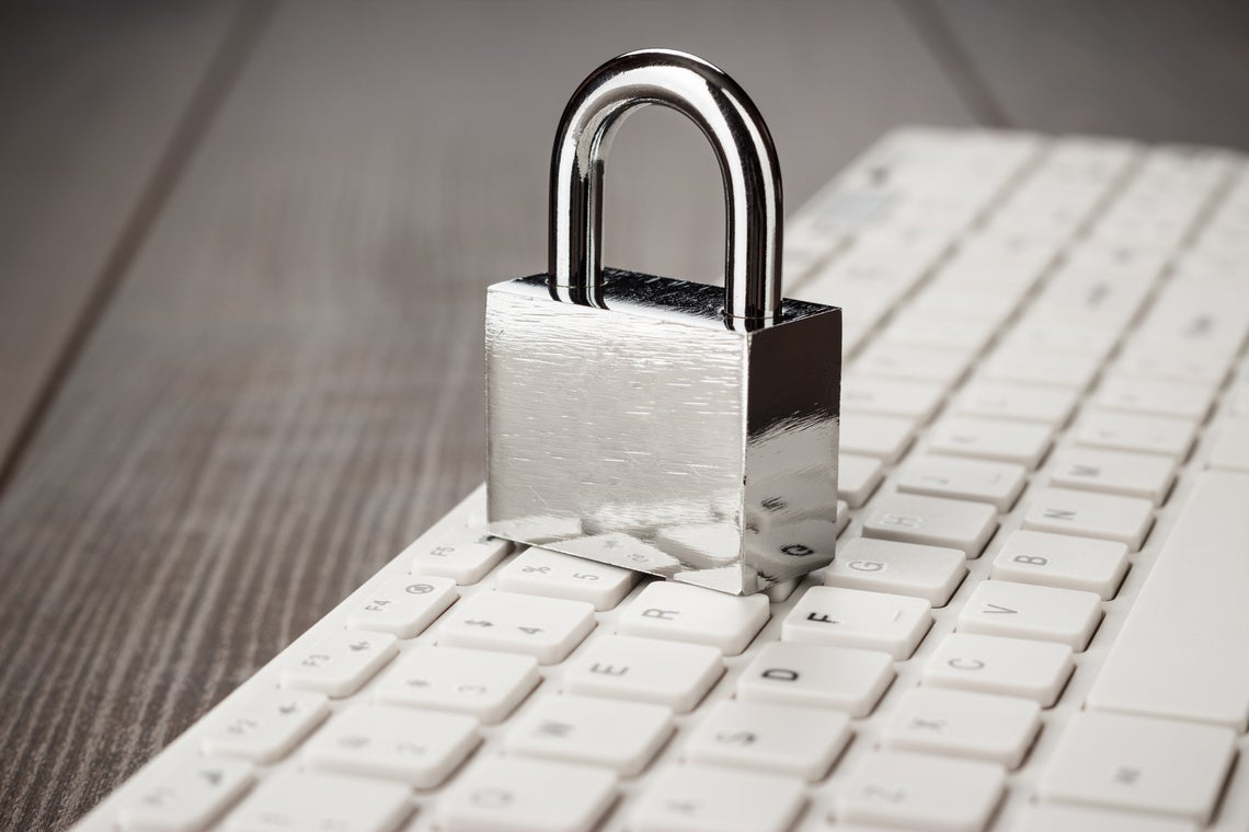 padlock and white computer keyboard on the wooden office table. privacy protection, encrypted connection concept