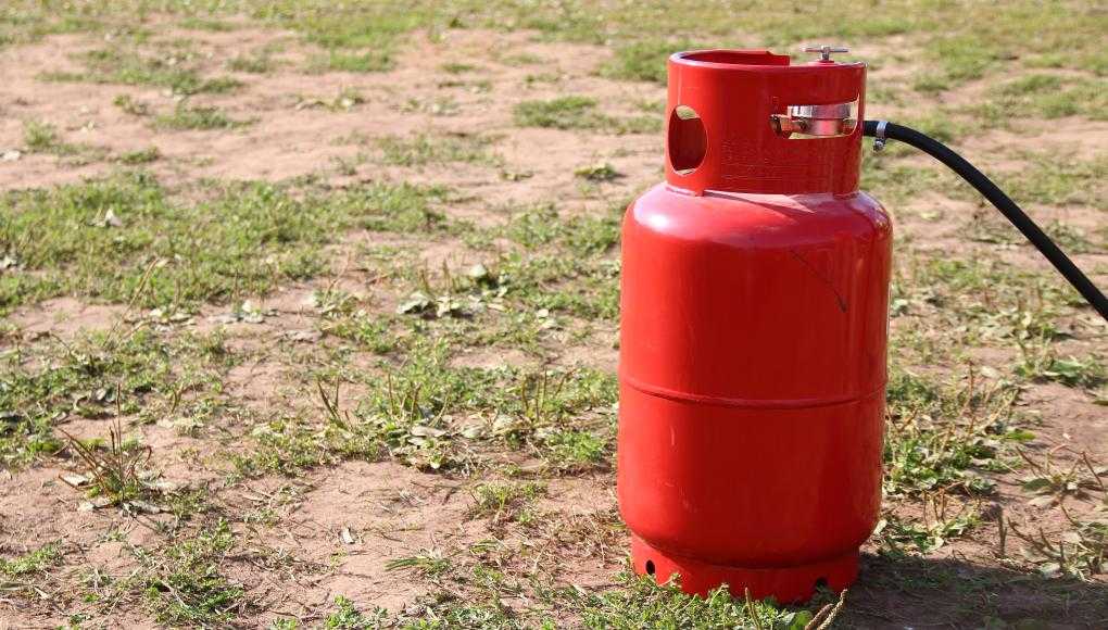 Red propane tank on the ground