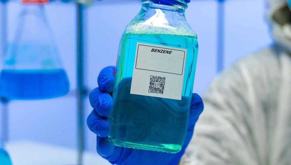 Someone in a lab holding a bottle of benzene