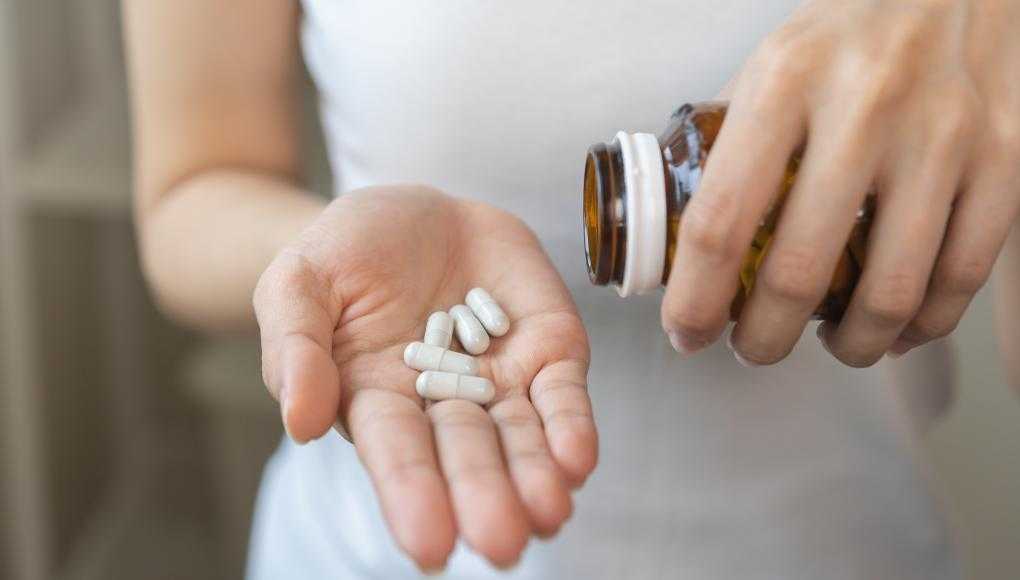 Woman pouring supplements into hand