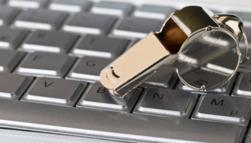 silver keyboard with silver whistle resting on top of the keyboard 