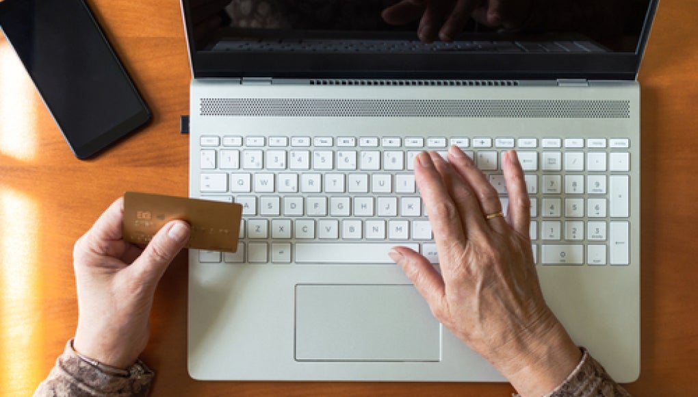 person sitting in front of laptop holding credit card in hand