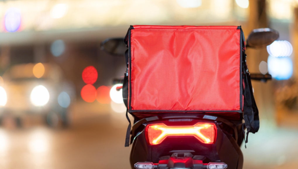 photo of a delivery driver with a red box of food 
