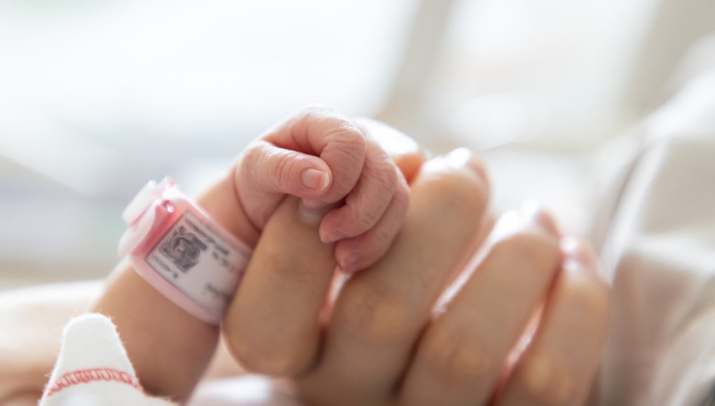 newborn baby holding onto moms hand