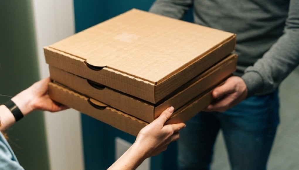 courier deliverying boxes of pizza to someone at their door 