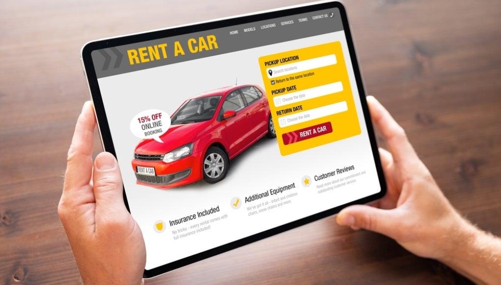 Person looking at car rental website on tablet computer to rent a car