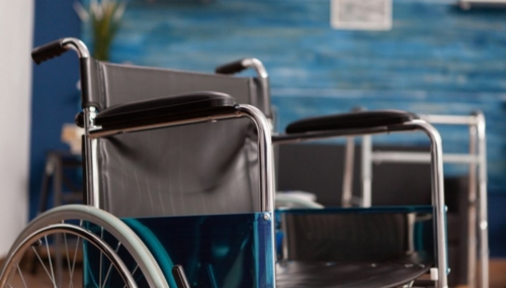 empty wheelchair in nursing home with a blue-grey background