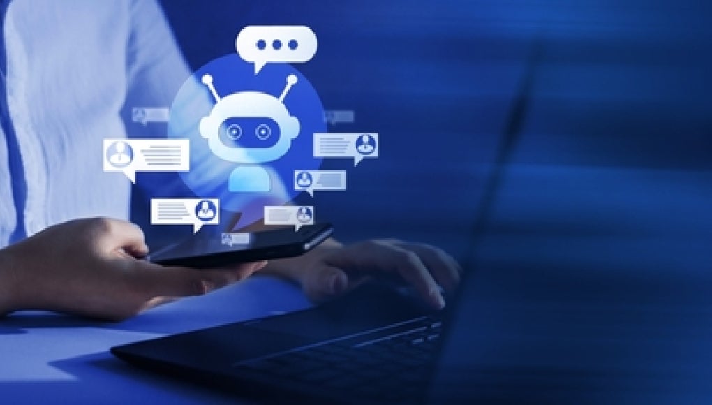 person sitting at laptop with AI chat bot floating above it 