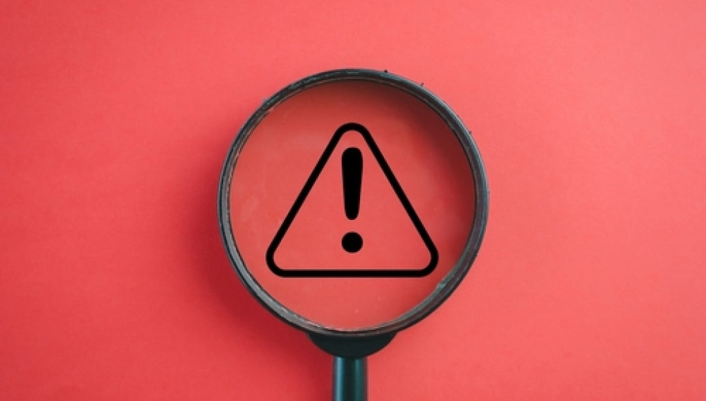 magnifying glass with red background and warning symbol