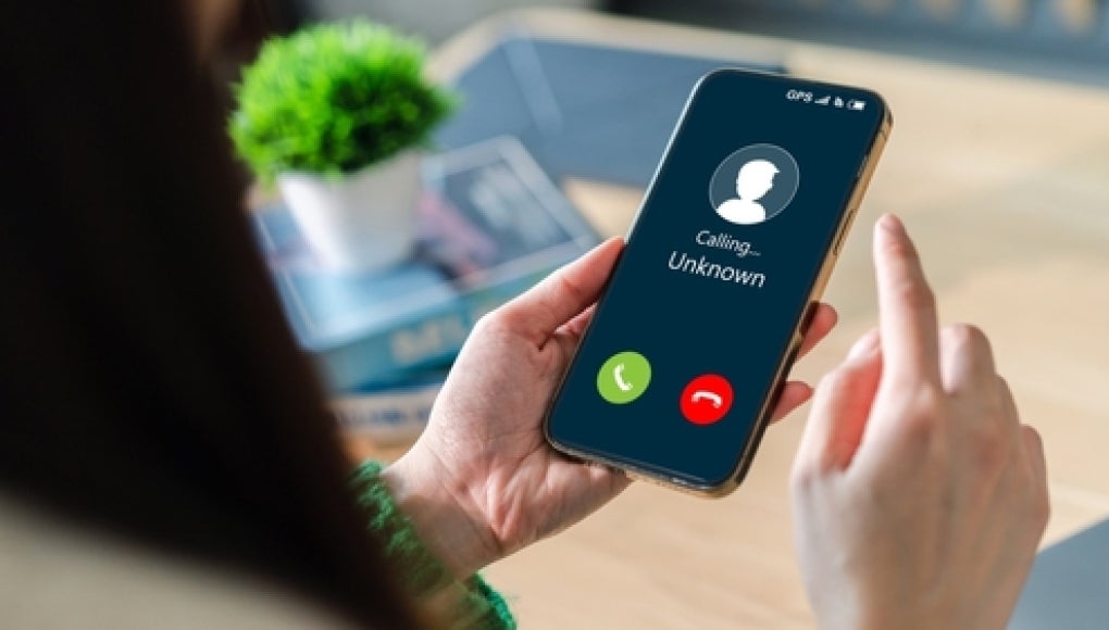 person holding phone with a unknown caller calling, possibly a robocaller or spam caller