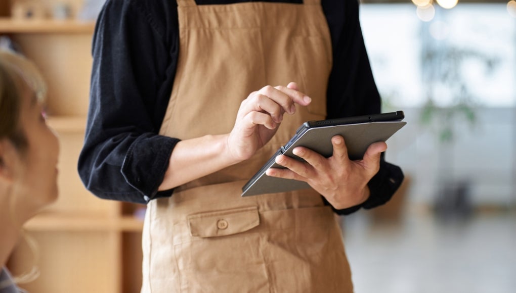 Asian male clerk taking orders at a cafe