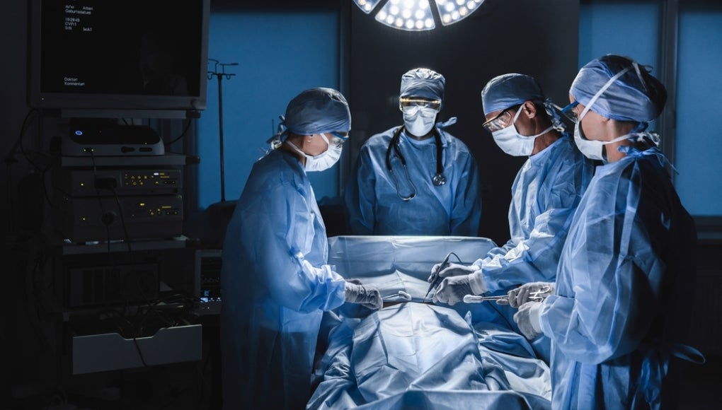 Diverse team of surgeons performing surgery on patient in hospital operating room. Urgent treatment, plastic surgery. Specialists saving patient`s life in operation theater.