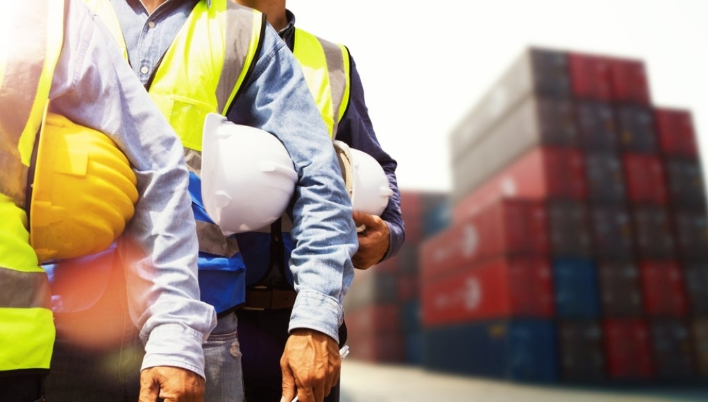 Multiethnic team male Engineer maintenance department site work container service : Group of male workers wearing safety vests and holding helmets outdoor container loading yard meeting teamwork.