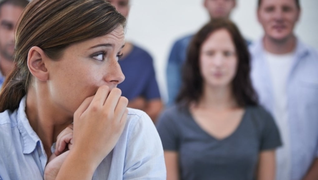 person nervously looking away with people behind them, staring at them