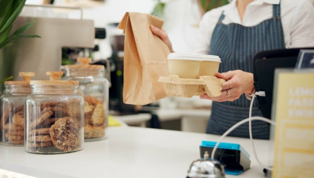 Barista, customer and takeaway coffee or giving at counter as breakfast order, morning or espresso. Person, hands and cafe shop or lunch beverage for small business food at bakery, latte or drink