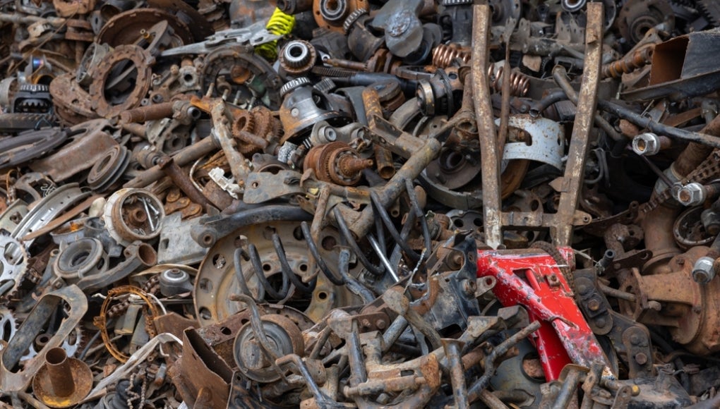 A pile of junk with a red tool on top. The pile is full of rusty parts and the red tool is the only thing that stands out