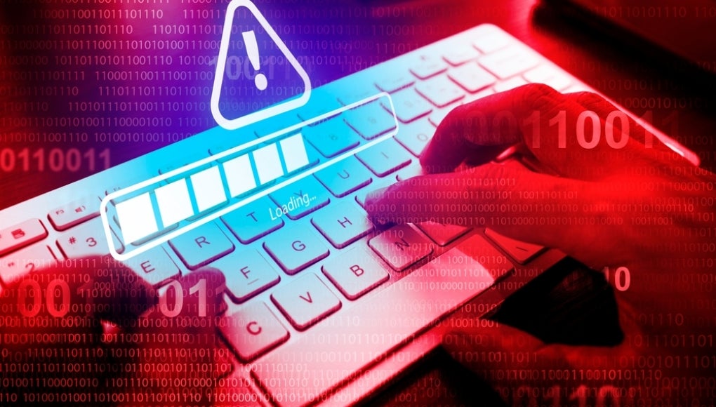 person typing on computer with a scam warning