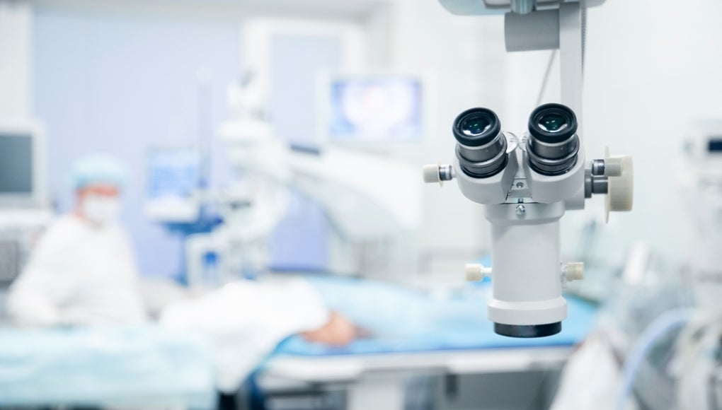 Lasik treatment operation, laser vision correction. Doctor examines fundus in microscope, patient under sterile cover.
