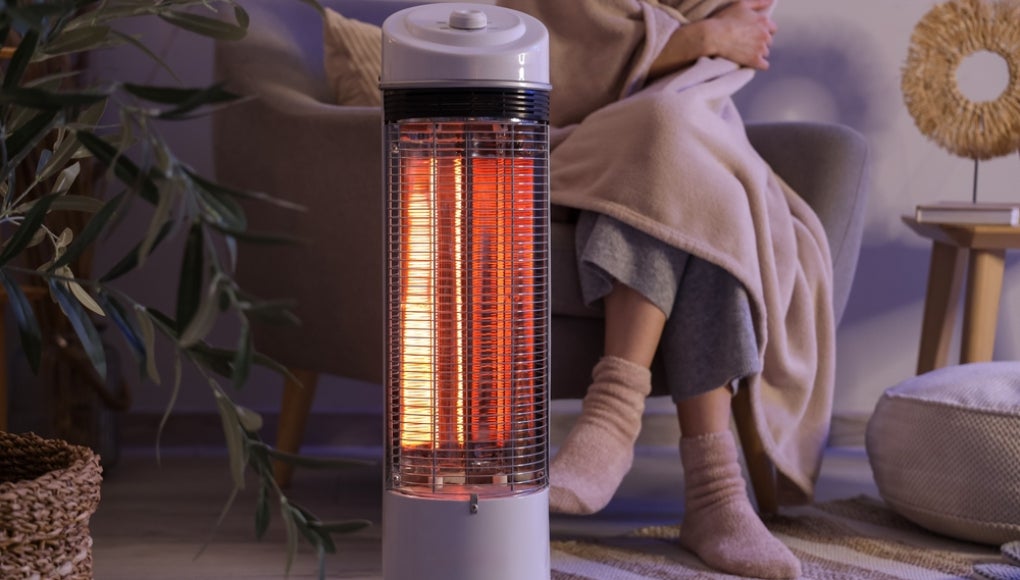 heater near a couch with a lady wearing a blanket