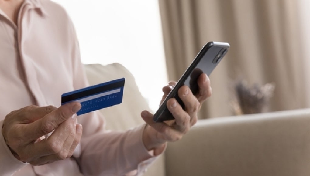 elderly person holding phone and card in hands