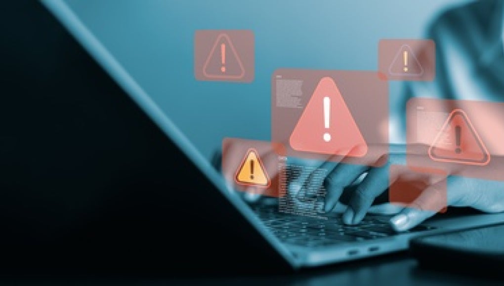 person at laptop with red warning signs 