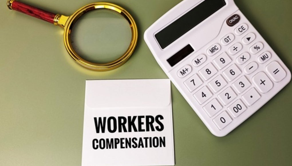 magnifying glass with calculator and notepad that reads 'workers compensation' 