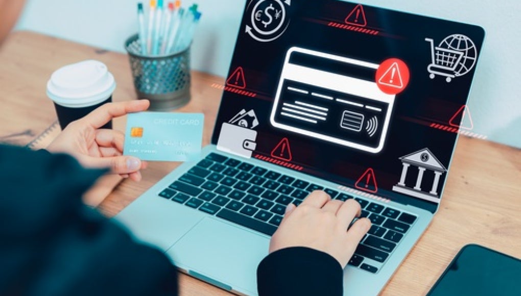 person sitting in front of laptop with error messages holding their card 