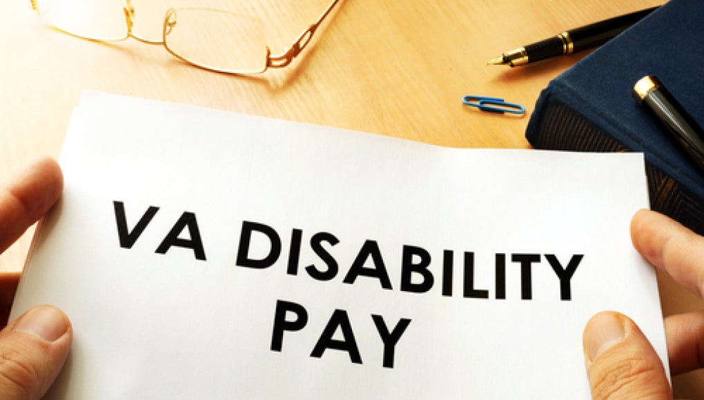 veterans affairs disability pay displayed on pile of papers that someone is holding.