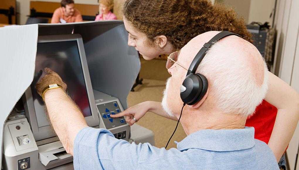 People with Disabilities Have a Right to Vote, too, Federal Law Says - A man teaching a girl about the machine.