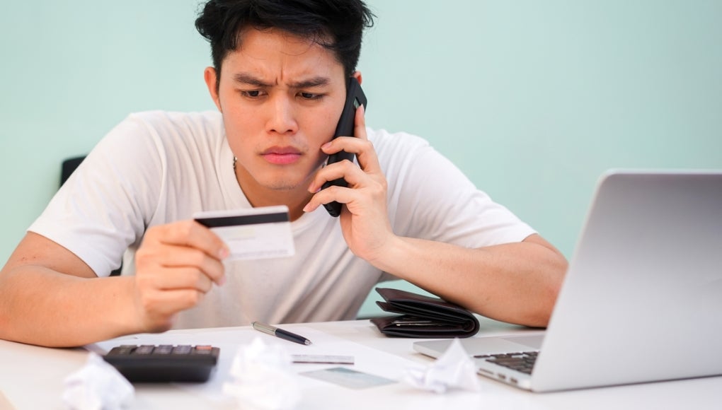 Man on phone looking at card