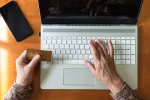 person sitting in front of laptop holding credit card in hand