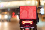 photo of a delivery driver with a red box of food 