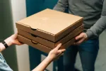 courier deliverying boxes of pizza to someone at their door 