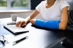 person with a arm cast sitting in front of a computer and keyboard