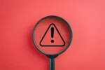 magnifying glass with red background and warning symbol