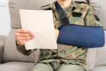 veteran in a arm sling reading a claim paper