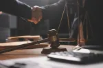 two people shaking hands with scales and gavel nearby