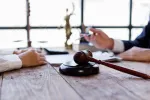 lawyer speaking wtih client, a gavel and scales are present on the table