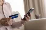 elderly person holding phone and card in hands