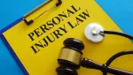 clipboard with yellow paper with the words "Personal Injury Law" on it, with a blue background, there is a stethoscope and gavel resting on top of the clipboard