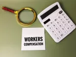 magnifying glass with calculator and notepad that reads 'workers compensation'