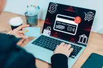 person sitting in front of laptop with error messages holding their card