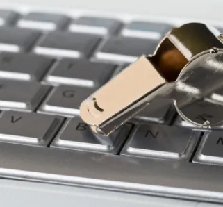 silver keyboard with silver whistle resting on top of the keyboard