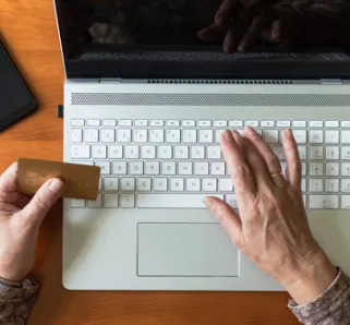 person sitting in front of laptop holding credit card in hand