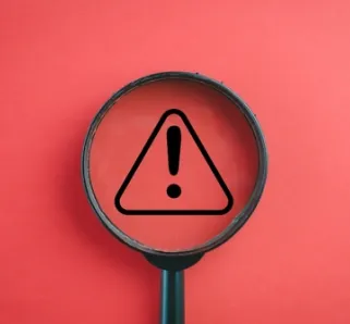 magnifying glass with red background and warning symbol