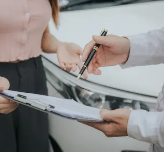 two people reviewing insurance claim with car in background