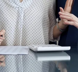two people sitting with one person putting their hand up to block the other one from touching them