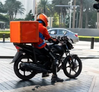 delivery person on a motorbike with a red delivery container on the back